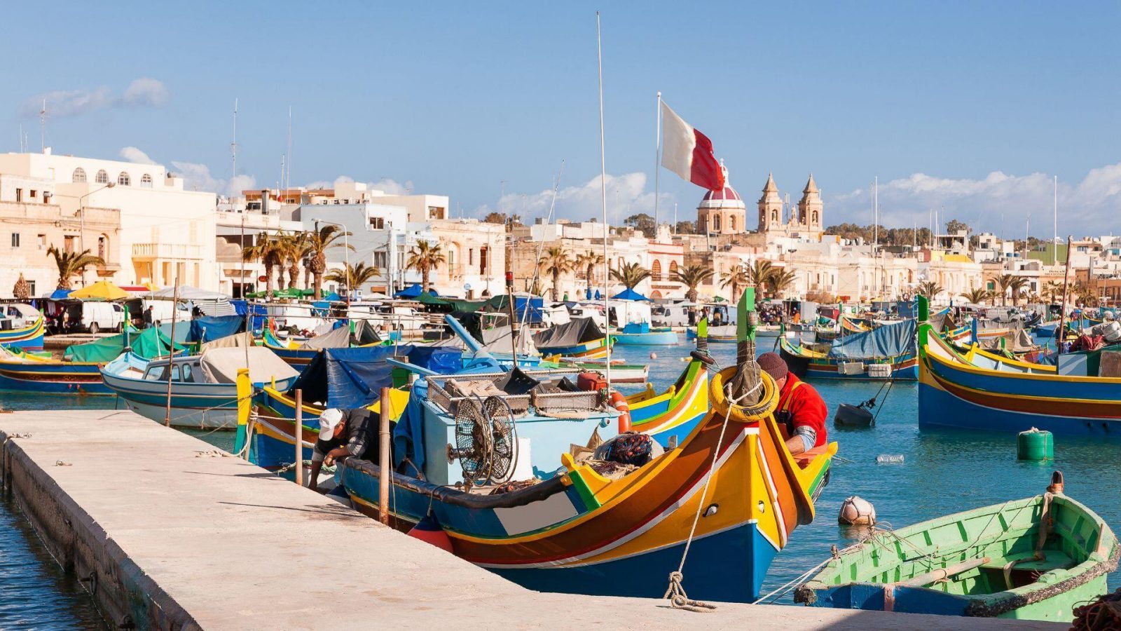 Zu sehen sind traditionelle, bunte Boote aus dem Mittelmeerraum, sogenannte Luzzu. Fischerdorf im Südosten Maltas. Ein früher Wintermorgen in Marsaxlokk, Malta. 